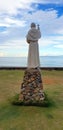 Stone Monument of the Man with Catholic Cross in Front of The Sea Royalty Free Stock Photo