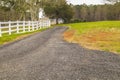 A gravel road along side a white fence