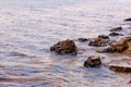 Stone near the river. Waves run on the coastline. Summer sunset. The sun`s rays are reflected in the water