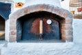 Stone oven with rusty metal door and a heat thermometer