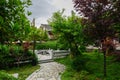 Stone path in garden before tile-roofed buildings on cloudy spring day