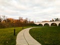 Stone path, a path in the park leading to a pedestrian bridge with arches under it. Landscape park in the fall. Royalty Free Stock Photo