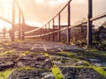 Stone path in town with green moss between joints in focus, Meatl rail and people walking in the background out of focus. Warm Royalty Free Stock Photo