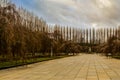 Stone pathway lined with bare winter trees leading to statue at Soviet War Memorial in Treptower Park, Berlin. Royalty Free Stock Photo