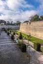 Stone pathway meanders through a lush park surrounded by towering trees in Mdina Old City Fortress Royalty Free Stock Photo