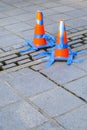 Stone patio with orange safety cones and blue painters tape blocking off loose bricks