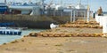 Stone pier with big white bollard and yellow metal chain for ships and white lighthouse. Royalty Free Stock Photo