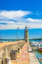 Stone pier mole with lighthouse, street lights and yachts on boat parking port marina in Desenzano del Garda Royalty Free Stock Photo