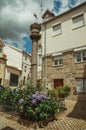 Stone pillory with flowered bushes in a small square Royalty Free Stock Photo