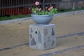 Stone planter with flowers near driveway of house