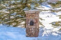 Stone post with mailbox and outdoor lamp against sunlit snow in Park City Utah