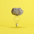 Stone put on light bulb floating on yellow background
