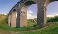 Stone railway ancient arch bridge over the green valley