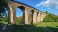 Stone railway ancient arch bridge over the green valley