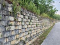 Stone Retaining Wall with Vegetation Along a Paved Pathway Royalty Free Stock Photo