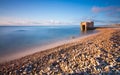 Stone and rocks beach with nobody close to a bunker and a scenic blue sky with clouds Royalty Free Stock Photo