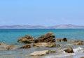 Stone rocks on coast in clear blue water with blue sky and mainland at horizon, view from kos, greece to turkey