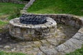 Stone round fountain with a protective grid of twisted prisms. forged steel bars go spiraled at the top. around the well there is