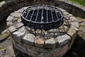 Stone round fountain with a protective grid of twisted prisms. forged steel bars go spiraled at the top. around the well there is Royalty Free Stock Photo