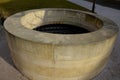 Stone round fountain with a protective grid of twisted prisms. forged steel bars go spiraled at the top. around the well there is Royalty Free Stock Photo