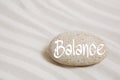 Stone in the sand with the word balance. Idea for wellness and r