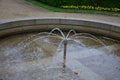 Stone sandstone circular fountain in the park. built of sandstone filled with water. lined with a light threshing gravel road with