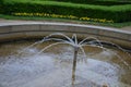 Stone sandstone circular fountain in the park. built of sandstone filled with water. lined with a light threshing gravel road with Royalty Free Stock Photo