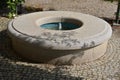 Stone sandstone circular fountain in the park. built of sandstone filled with water. lined with a light threshing gravel road with