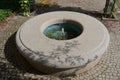 Stone sandstone circular fountain in the park. built of sandstone filled with water. lined with a light threshing gravel road with Royalty Free Stock Photo
