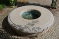 Stone sandstone circular fountain in the park. built of sandstone filled with water. lined with a light threshing gravel road with