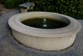 Stone sandstone circular fountain in the park. built of sandstone filled with water. lined with a light threshing gravel road with Royalty Free Stock Photo