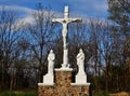 Stone sculpture featuring three statues with Jesus Christ on cross surrounded by leafless trees