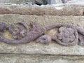 Stone sculptured statue of decorated shape on grunge stone wall