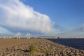 Stone sea promenade in the sandy desert against the cable-stayed bridge and the modern city under a heavy blue sky