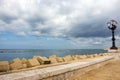 Stone seaside with iron street lantern on cloudy day. Adriatic seascape. Italian panoramic coastline. Italian south background. Royalty Free Stock Photo