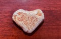 Stone shaped like a heart on a wooden surface in red tone. Heart made of natural stone on a wooden background. Valentine`s day an Royalty Free Stock Photo