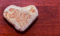 Stone shaped like a heart on a wooden surface in red tone. Heart made of natural stone on a wooden background. Valentine`s day an Royalty Free Stock Photo