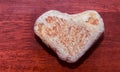 Stone shaped like a heart on a wooden surface in red tone. Heart made of natural stone on a wooden background. Valentine`s day an Royalty Free Stock Photo