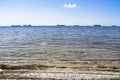 Stone shore with a view of the clear and transparent sea and cargo ships on a clear Sunny day. Calm summer seascape Royalty Free Stock Photo