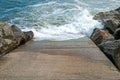 Stone slipway with blue ocean sea breaking waves and rocks