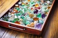 a stone sorting tray containing a variety of raw birthstones