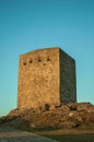 Stone square tower over rocky hill on sunset Royalty Free Stock Photo