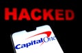 Capital One Bank logo on the smartphone and red alerting word HACKED on the blurred background. Conceptual photo for data breach Royalty Free Stock Photo