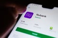 Nubank app in a Play Market seen on a smartphone screen and a finger touching pointing at it