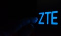 ZTE Corporation logo on the screen in a dark room and a hand pointing at it. ZTE is Royalty Free Stock Photo