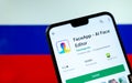 FaceApp logo on the screen of smartphone with the flag of Russia at the blurred background behind it. Conceptual editorial illustr