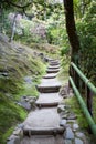 Stone stair pasing in green moss garden, rails from bamboo. Kyoto, Japan Royalty Free Stock Photo