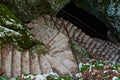 A stone staircase covered with autumn leaves that descends like a snake into a cave