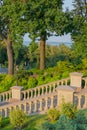 Stone staircase with decorative handrails on the background of the green park zone and blue pond.