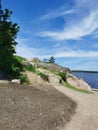 A stone staircase on the shore of the Vyborg Bay in the Monrepos Park of the city of Vyborg against the background of a blue sky Royalty Free Stock Photo